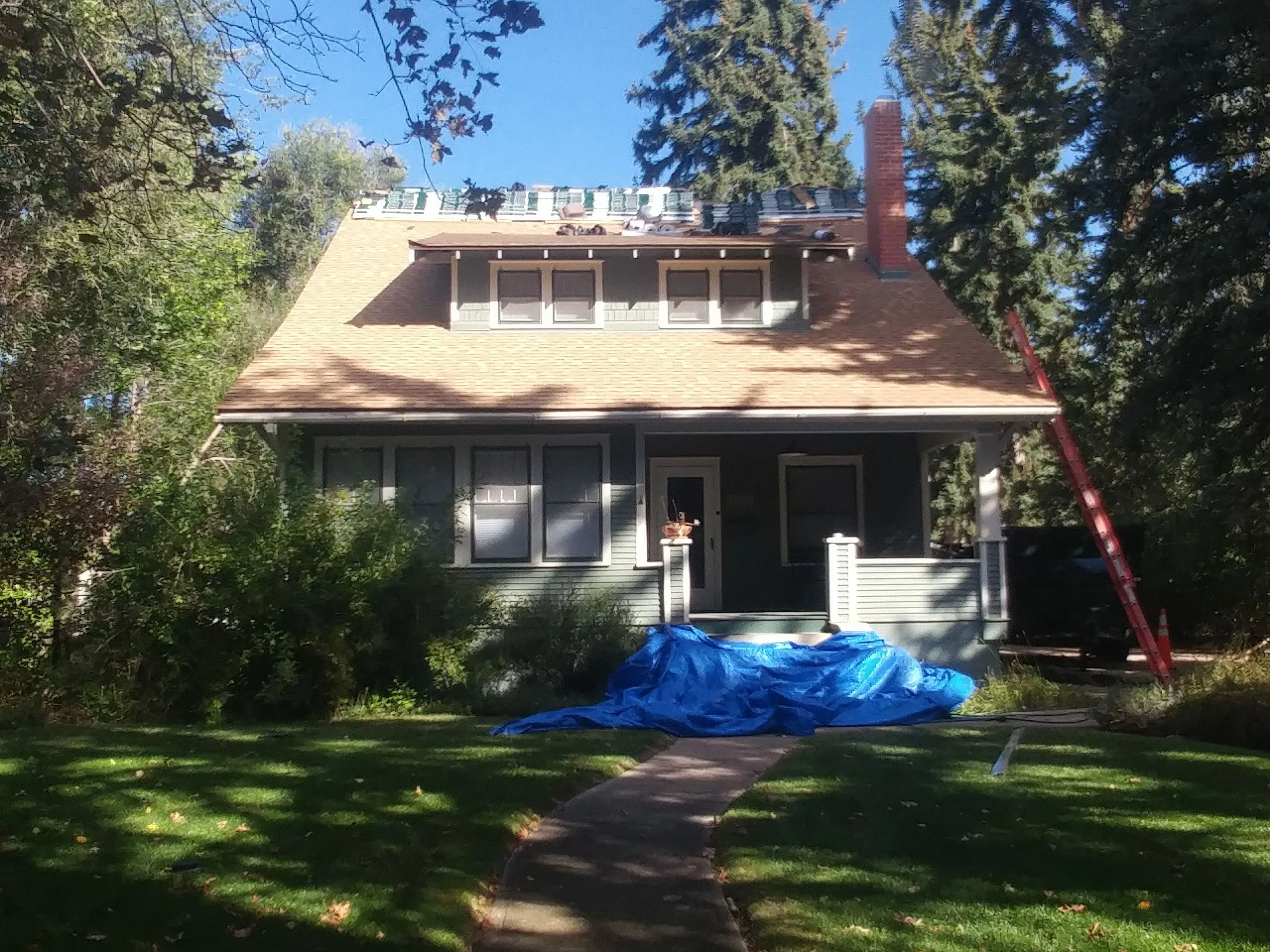 Residential Roof being redone with ladder on side and shingles on roof