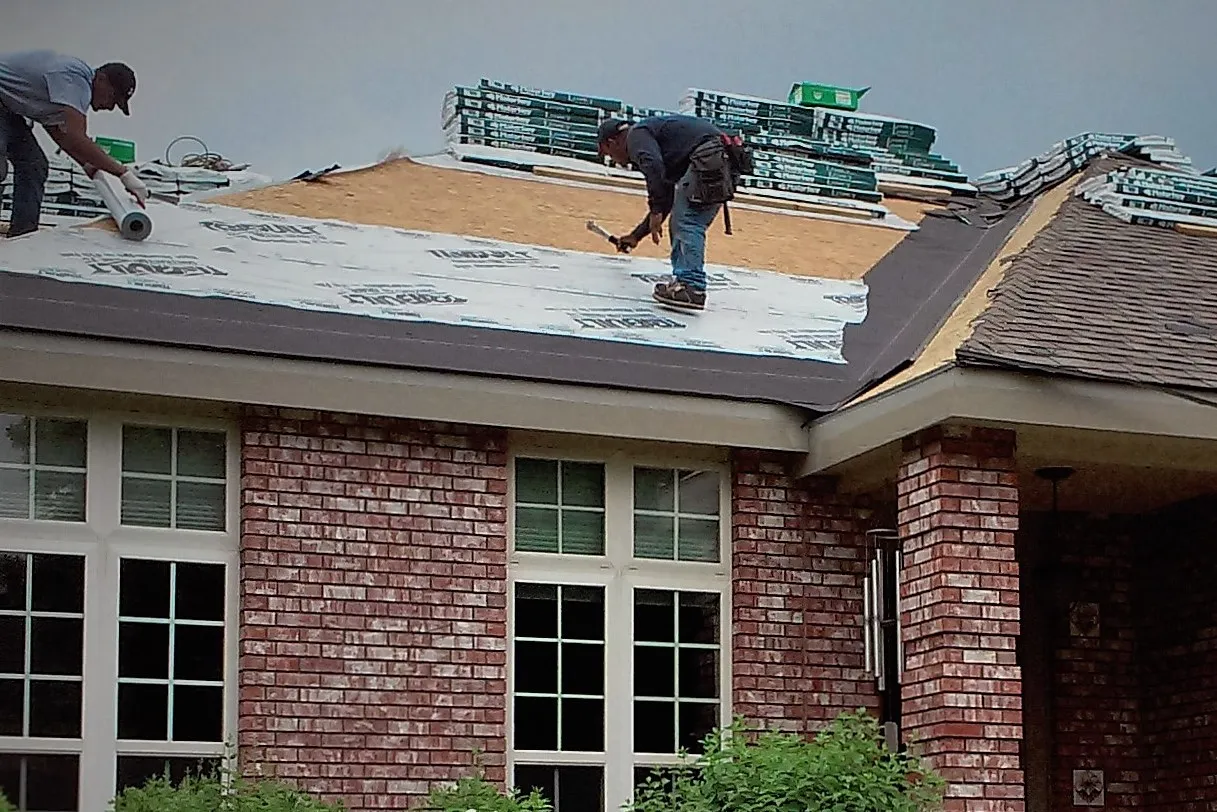 Roof with no shingles and man repairing roof